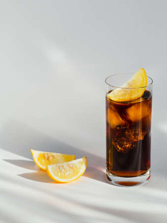 Glass of cola with ice and lemon on white backgroundの写真素材