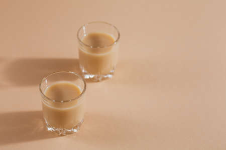 Short glasses of Irish cream Liquor or Coffee Liqueur on light beige background