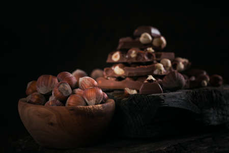 Pile of hazelnut milk chocolate and nuts on dark wooden backgroundの写真素材