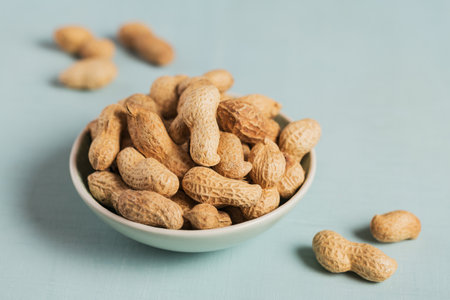 Pile of Peanuts in a bowl on a light blue background. Fresh nuts in their shells.の写真素材