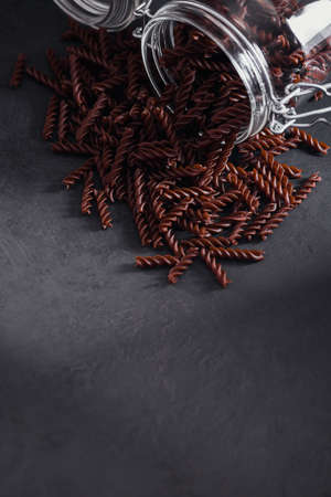 Organic uncooked Buckwheat Fusilli pasta in a glass jar on dark background. Wholegrain gluten free noodles. Healthy food concept.の写真素材