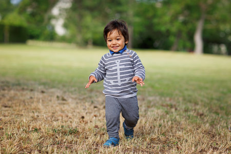 Portrait of a little eastern handsome baby boy playing outdoors in the park. Arabian child fun on the street.の写真素材