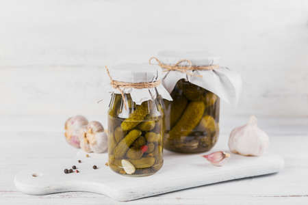 homemade canning. Marinated cucumbers gherkins with dill and garlic in a glass jar on the white...