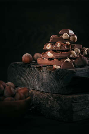 Pile of hazelnut milk chocolate and nuts on dark backgroundの写真素材