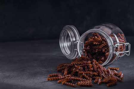Organic uncooked Buckwheat Fusilli pasta in a glass jar on a dark background. Wholegrain gluten free noodles. Healthy food concept.の写真素材