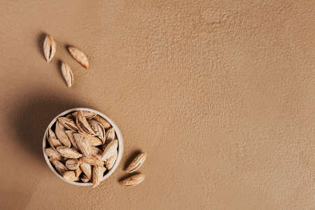 Pile of Almond nuts in a bowl on a white background. Fresh nuts in their shells.