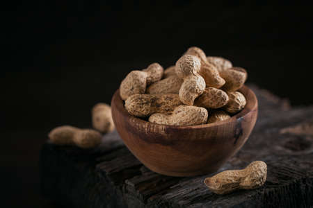 Pile of Peanuts in a bowl on a dark wooden backgroundの写真素材