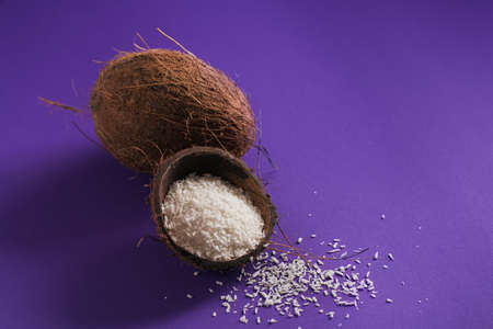 Whole coconut with coconuts flakes on a perple backgroundの写真素材