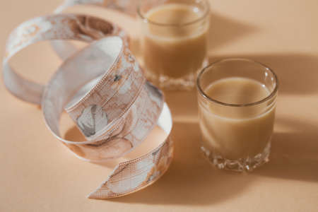 Short glasses of Irish cream Liquor or Coffee Liqueur with ribbon on light beige backgroundの写真素材