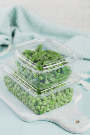 Plastic container with organic deep frozen vegetables on a tableの写真素材