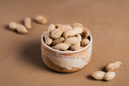 Pile of Peanuts in a bowl on a brown background