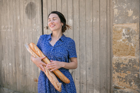 Young woman standing with french baguettes in the countrysideの写真素材