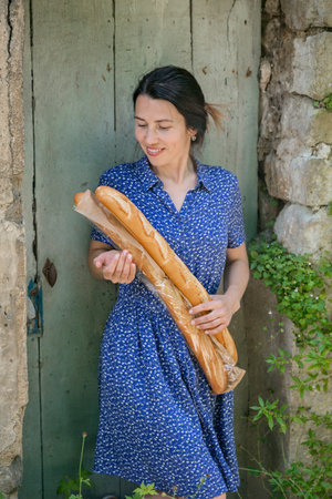 Young woman standing with french baguettes in the countrysideの写真素材