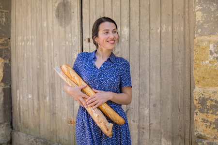 Young woman standing with french baguettes in the countrysideの写真素材