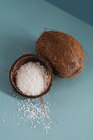 Whole coconut with coconuts flakes on a blue background