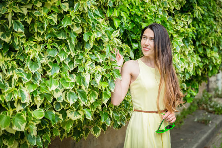 Woman staying surrounded by lush green plants, touching leavesの写真素材