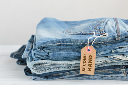 Stack of blue jeans and tag with inscription second hand on white backgroundの写真素材