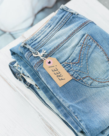 Stack of blue jeans and tag with inscription free on white background