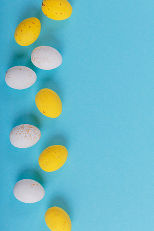 Minimalistic easter background of chocolate candy yellow and white eggs on a blue backgroundの写真素材