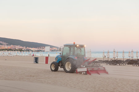 Evening empty beach. Tractor smoothes the sand on public beach by the seaの写真素材