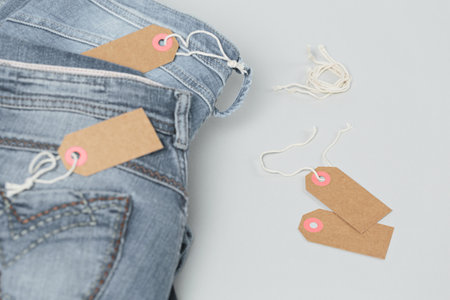 Stack of blue jeans and empty tags on white backgroundの写真素材