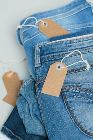 Stack of blue jeans and empty tags on white backgroundの写真素材