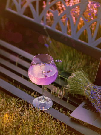 Laptop, bouquet of flowers and summer cocktail on bench among lavender fieldの写真素材