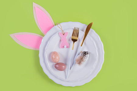 Table place setting and festive easter decor on pastel green background