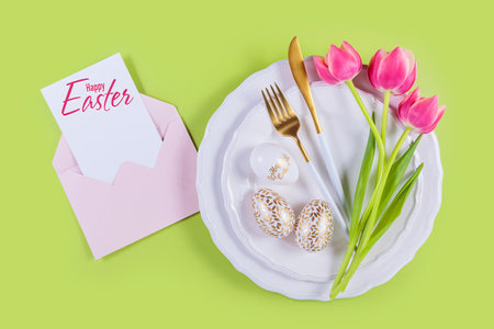 Pink tulips and table place setting and card with inscription Happy Easter
