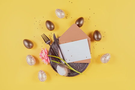 Table place setting with empty greeting or invitation card and Easter eggsの写真素材