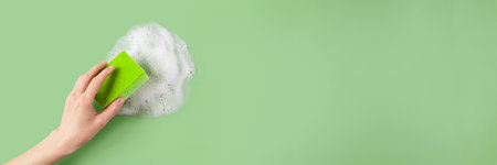 Womans hand holding washing sponge and wiping soap suds