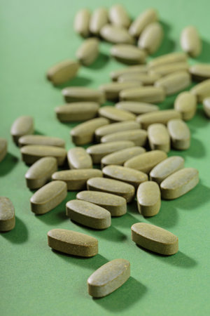 Herbal and Vitamin Green pills freely laid on green backgroundの写真素材