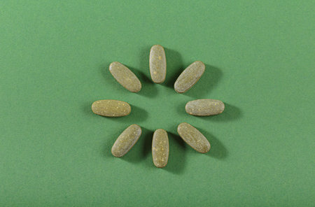 Herbal and Vitamin Green pills freely laid on green backgroundの写真素材