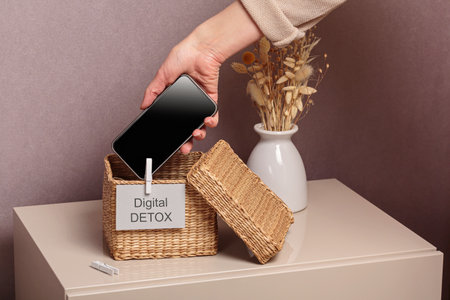 Woman putting phone into box with different gadgets at homeの写真素材