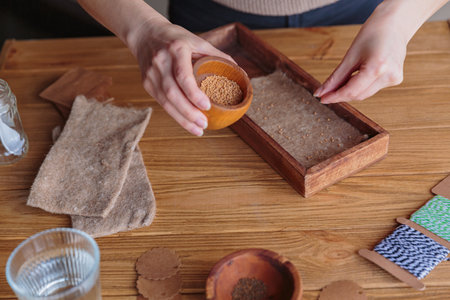 Woman planting seeds in wooden box, growing microgreens at homeの写真素材