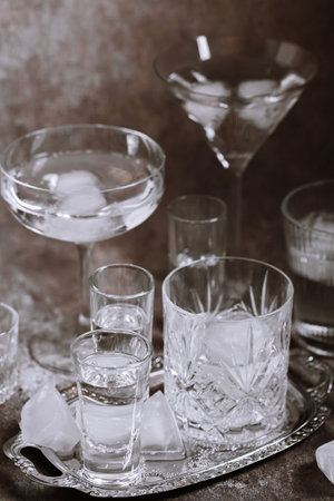 Collection of various glasses on silver tray filled with clear cold drinksの写真素材