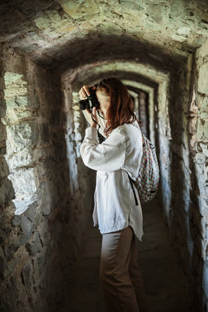 Woman takes pictures while standing in corridor of ancient castleの写真素材