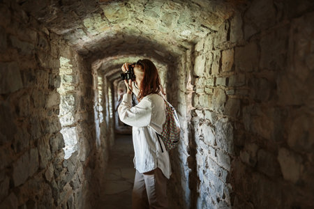 Woman takes pictures while standing in corridor of ancient castleの写真素材