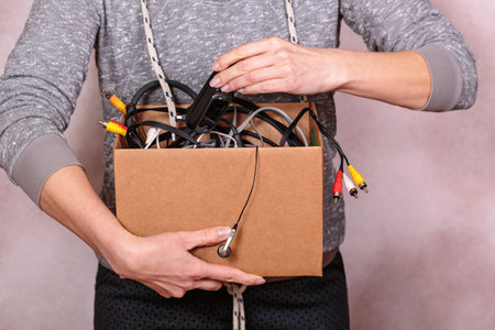 Hands of woman sorting through electronic cables and gadgetsの写真素材
