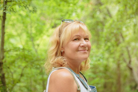 Middle aged woman with backpack walking along forest pathの写真素材