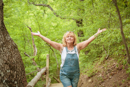 Middle aged woman walking along forest path with backpackの写真素材