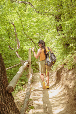 Middle aged woman with backpack walking along forest path