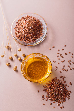 Brown linen seeds, flaxseed vegetable oil on beige backgroundの写真素材