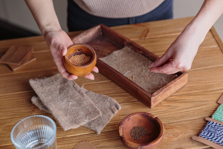 Woman planting seeds in wooden box, growing microgreens at homeの写真素材