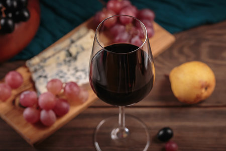 Glass of red wine served with cheese plate and fruitsの写真素材