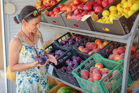 Mature woman choosing fruit in street storeの写真素材