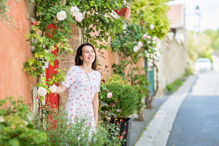 Young woman staying near red door on the street in old townの写真素材