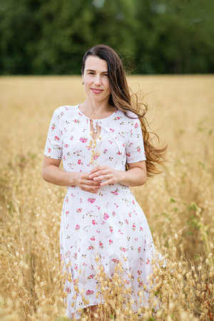Young woman in white midi dress walking across the fieldの写真素材