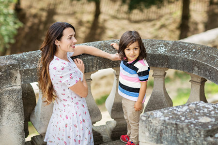 Mom and cute little boy are walking in picturesque old parkの写真素材