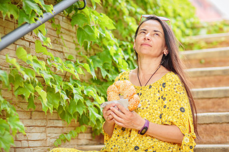 Attractive brunette woman sitting on stairs with bagelの写真素材